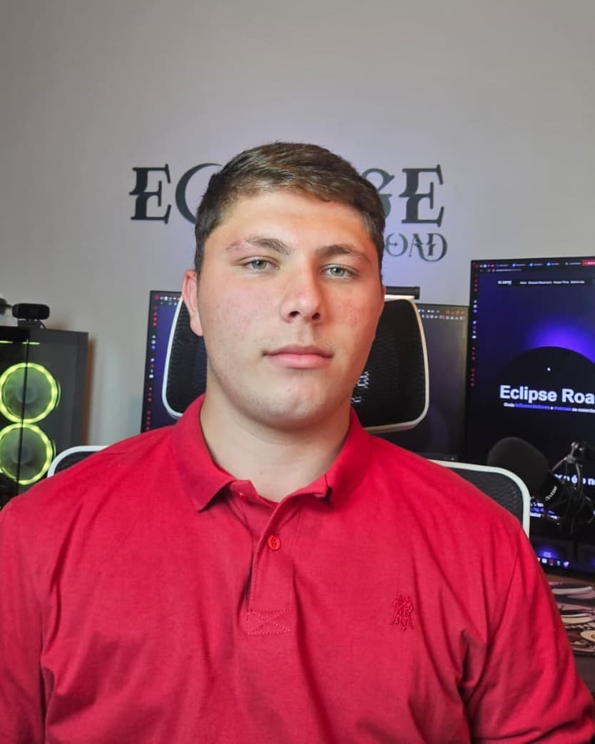 Guilherme Vieira de camisa polo vermelha, diante da parede com o nome Eclipse Road