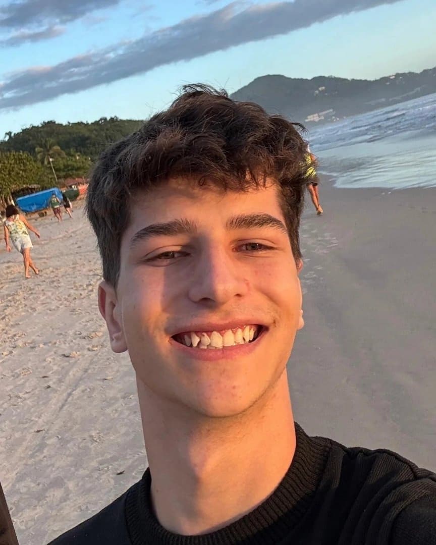Gustavo Felipe sorrindo, numa praia