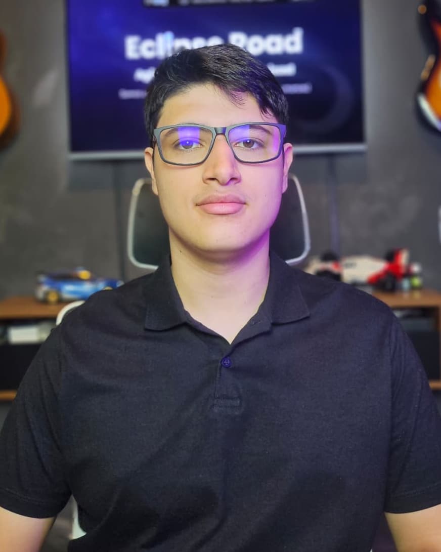 Felipe Domingues de óculos e camisa polo preta, diante de uma tela com a marca Eclipse Road
